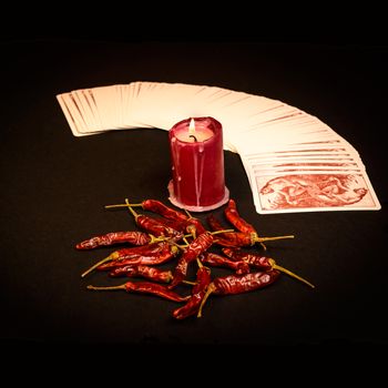 In the pictured a deck of cards open fan , a red candle and red pepper dry.