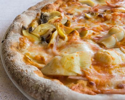 In the picture a  half pizza with tomato, mozzarella, mushrooms, ham and artichokes