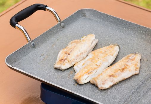 Pictured three fillets of sea bream cooked on the grill outdoor.