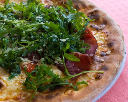 In the picture Italian pizza  with Arcula,cherry tomato,tomato,cheese,mozzarella,parmesan and Bresaola.