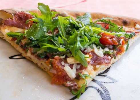In the picture Italian pizza close-up with Arcula,cherry tomato,tomato,mozzarella,cheese,parmesan and Bresaola.