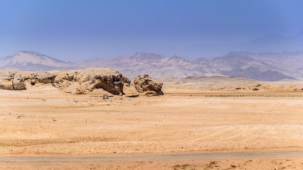 In the picture the rocky desert that surrounds the national park of Ras Mohammed in Egypt , and in the background the mountains of Sinai .