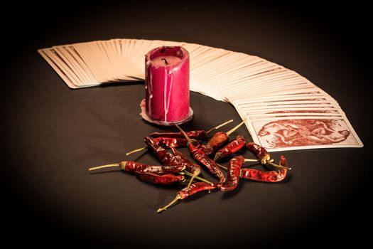 In the pictured a deck of cards open fan , a red candle and red pepper dry.