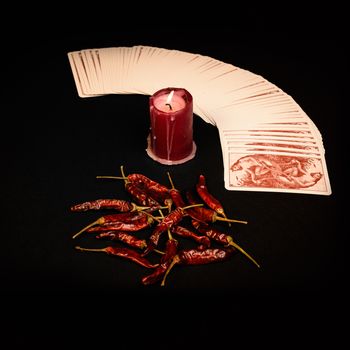 In the pictured a deck of cards open fan , a red candle and red pepper dry.