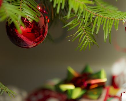 Gifts in the background with a christmas ornament hanging from the tree up front