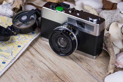 In the picture an analog camera film , a compass and a map, on the sides shells and decorative stones .