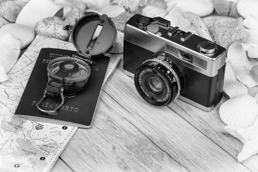 In the picture an analog camera film , a compass, passaport and a map, on the sides shells and decorative stones .