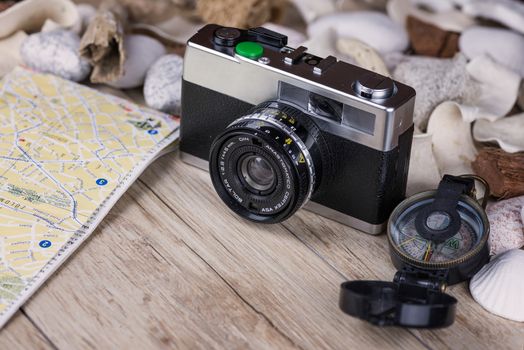 In the picture an analog camera film , a compass and a map, on the sides shells and decorative stones .