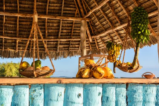 In the picture beach bar in Nungwi ( Zanzibar ) at sunset , with exposed coconut , banana and tropical fruit .This bar is made with cane bamboo,wooden and straw rope.