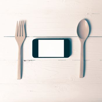 spoon and smart phone concept eating social over table background vintage style