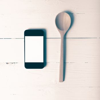 spoon and smart phone concept eating social over table background vintage style