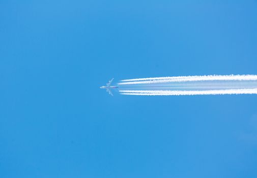 A plane flying on a clear blue sky with vapor trail