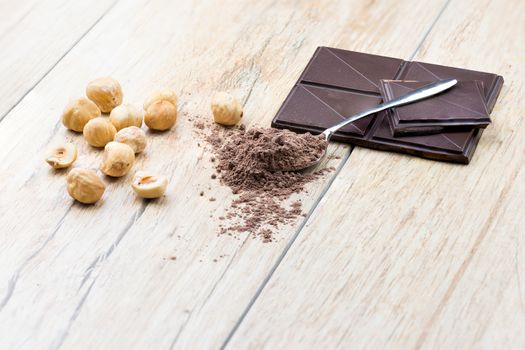 A side  view of chocolate, hazelnuts clean and covered teaspoon cocoa.