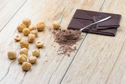 A side  view of chocolate, hazelnuts clean and covered teaspoon cocoa.