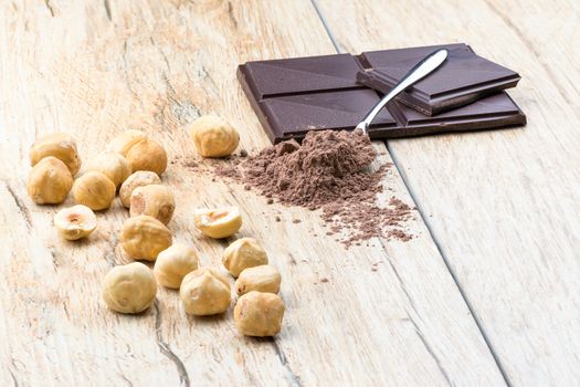 A front view of chocolate, hazelnuts clean and covered teaspoon cocoa.