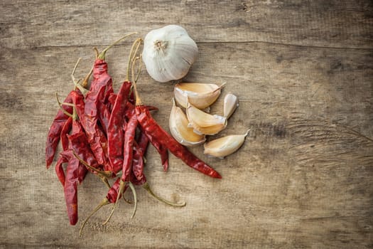 Dried red chili pepper and fresh garlic on wooden background .