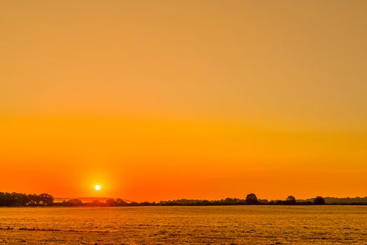 Countryside landscape with a beautiful sunrise in orange colors