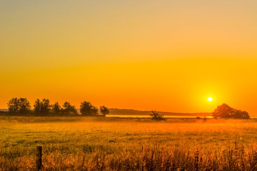 Sunrise over a field with mist in the morning