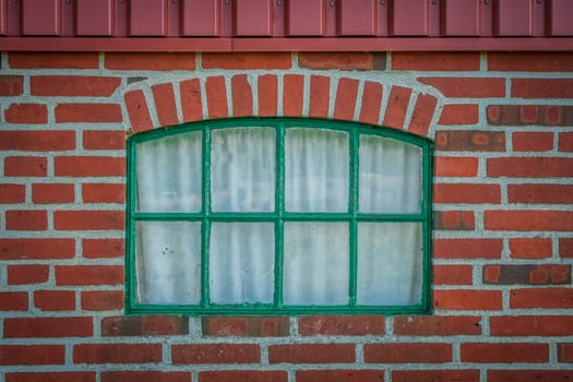 Green window on a house made of red bricks