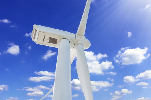 Wind turbine for alternative energy in front blue sky.