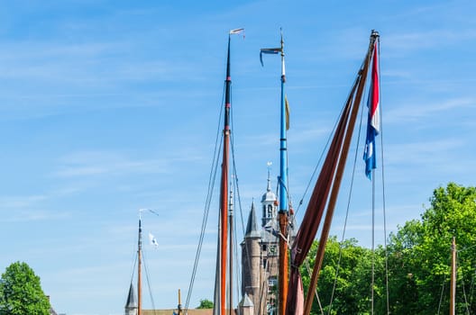 Various ship masts with Dutch flag against a bright blue sky.