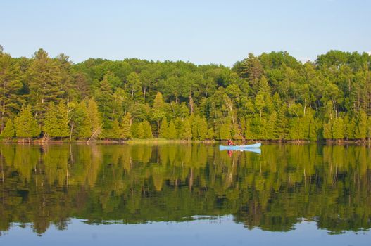 Man paddling a canoe on a lake in the summer in Ontario, Canada