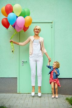 mother and child with colorful balloons on green background