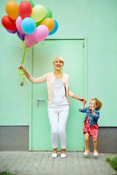 mother and child with colorful balloons on green background