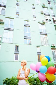 Happy young woman with colorful latex balloons, outdoor