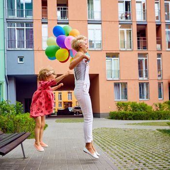 summer holidays, celebration, family, children and people concept - mother and child with colorful balloons, jumping
