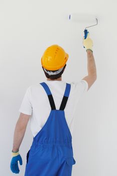 workman in helmet painting white wall