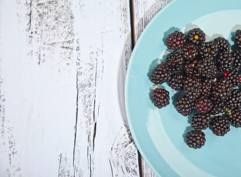 Blackberries on blue plate on wooden background