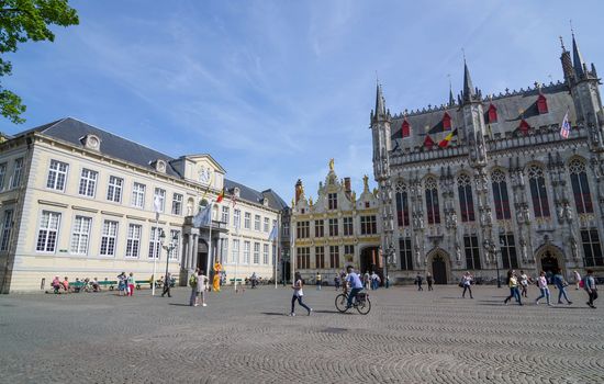 Bruges, Belgium - May 11, 2015: Tourist on Burg square with City Hall in Bruges, Belgium on May 11, 2015. The historic city centre is a prominent World Heritage Site of UNESCO.