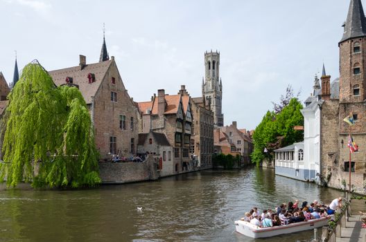 Bruges, Belgium - May 11, 2015: Tourist visit Rozenhoedkaai (The Quai of the Rosary) in Bruges, Belgium. One of Bruges most picturesque locations. With a view of the Bruges Belfry in the distance.