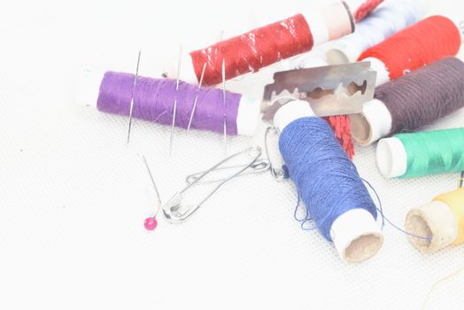 set of colored threads with needles and blade for sewing