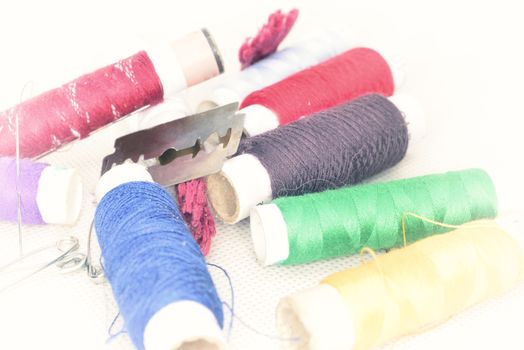 set of colored threads with needles and blade for sewing