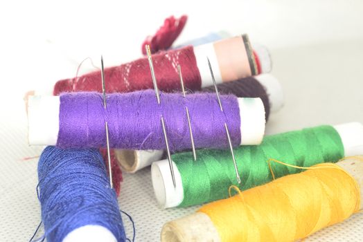 set of colored threads with needles and blade for sewing