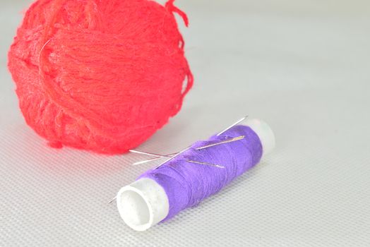 purple yarn and red clew  with needles for sewing