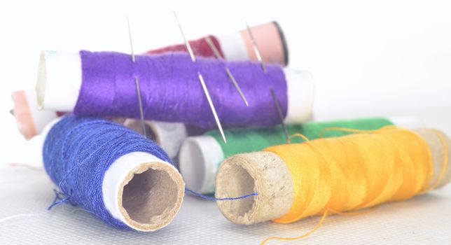 set of colored threads with needles and blade for sewing