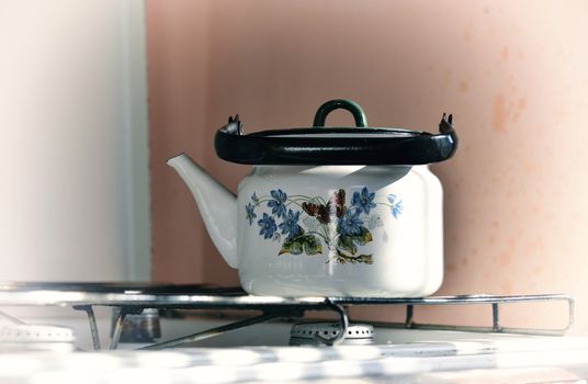 old white kettle with painting on a gas stove