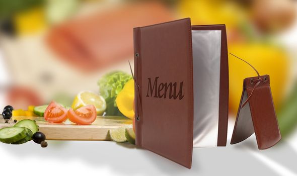 opened empty vegetarian brown leather menu and bill in a restaurant or cafe against the background of vegetables and fish