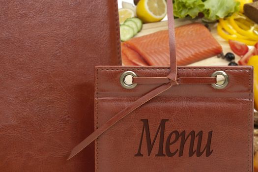 brown leather menu in a restaurant or cafe against the background of vegetables and fish