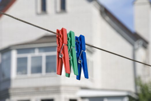 three colored household clothespins on  clothes line