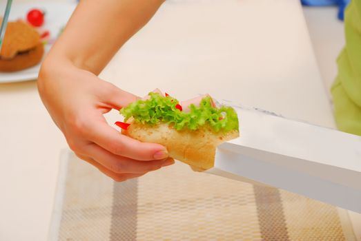 hands pack up submarine sandwich in paper bag at kitchen