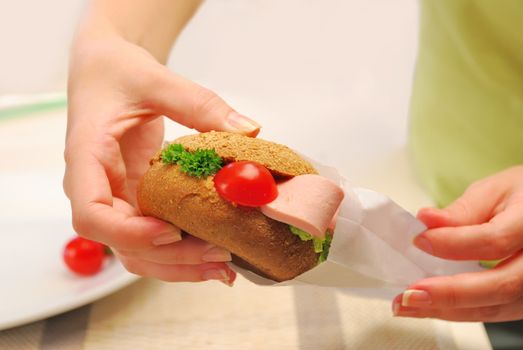 hands pack up  sandwich (hamburger) in paper bag at kitchen