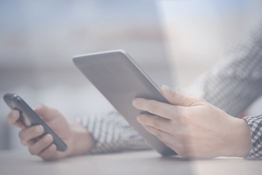 Businesswoman at office working with digital tablet and smartphone beinhd the window