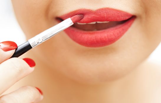 Woman applying red lipstick. Close-up view on face