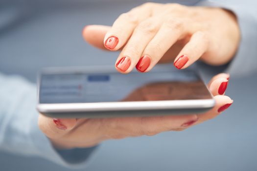 Woman with red manicure using tablet computer. Horizontal photo