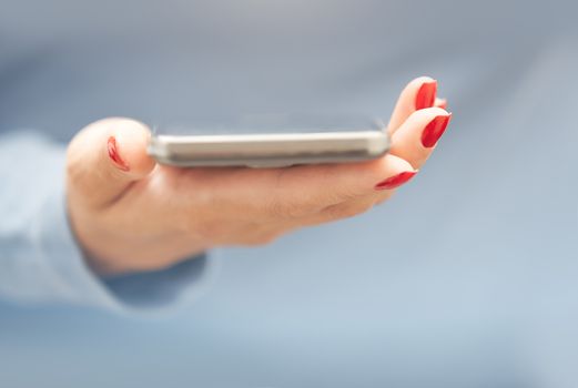 Woman with red manicure with smartphone. Horizontal photo