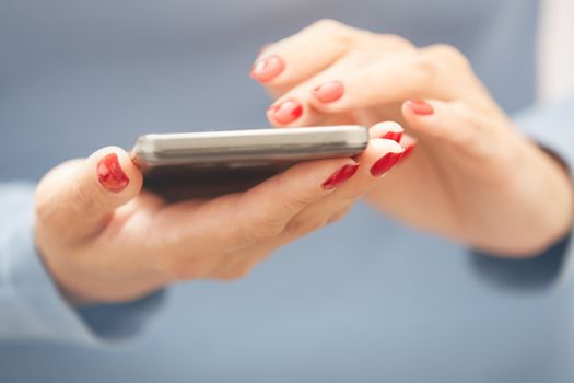 Woman with red manicure using smartphone. Horizontal photo